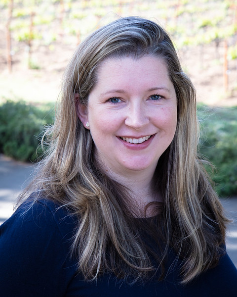 Megan Carter, a smiling woman with long, blond hair, in front of the Hendry vineyard